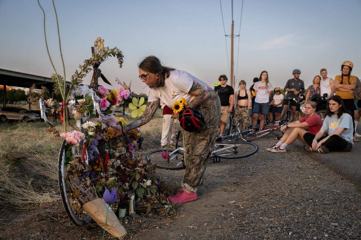Rucha Powers, whose son Lincoln Sabini was killed while bicycling at UC Davis, adds flowers to a ghost bike during a memorial ride on campus Wednesday.