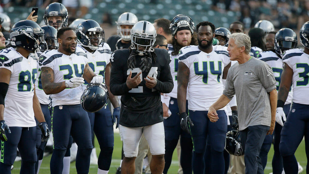 Raiders running back Marshawn Lynch meets with his former team, the Seattle Seahawks, and coach Pete Carroll, right, before a 2017 preseason game in Oakland. Reports are Lynch could re-sign with the Seahawks in time for Sunday night’s game against the 49ers.