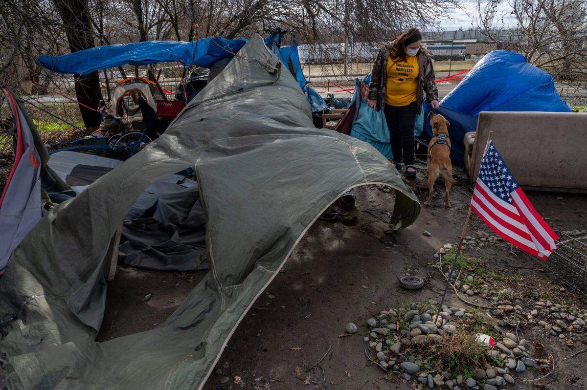 Crystal Sanchez with Sacramento Homeless Union checks on the homeless encampment near Basler and N. 18th Street where wind and fallen branches damaged tents in Sacramento on Wednesday, Jan. 27, 2021.