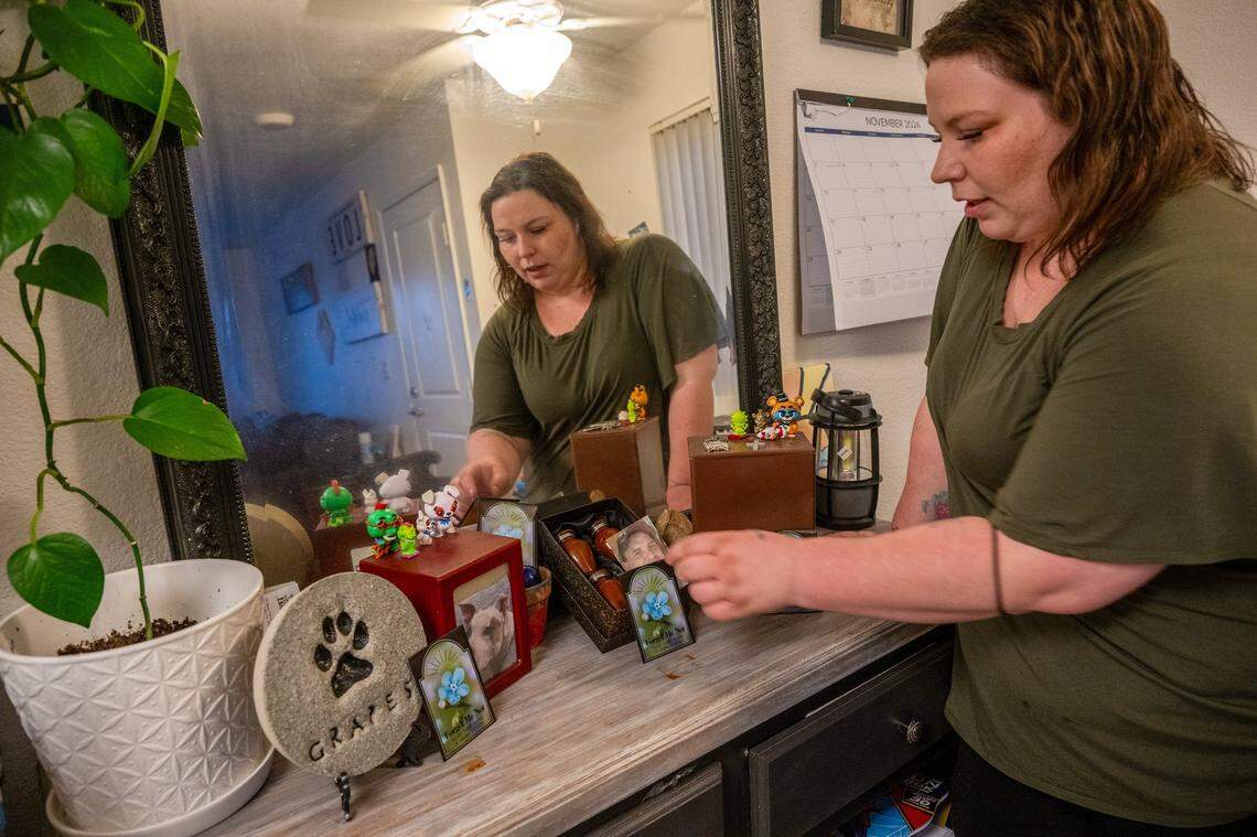 Katie Horton places cards with a forget-me-not flower picture near a memorial for her mother, her children’s father and her dog in her apartment in Lincoln on Wednesday. She said she still grieves for all three.