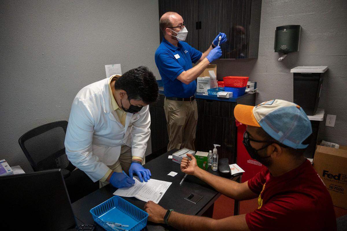 Pharmacy intern Patrick Cervania, left, fills out paperwork as Clint Hopkins, pharmacist of Pucci’s Pharmacy in East Sacramento, prepares a vaccine for Ryan Stone, a Midtown resident who came in for monkeypox and flu vaccines on Wednesday.