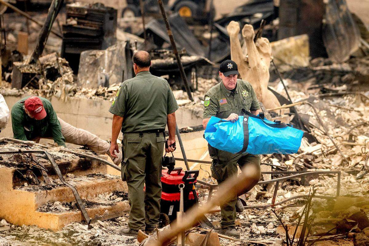 Siskiyou County Sheriff’s deputy Michael Johnson carries remains of a McKinney Fire victim from a destroyed home on Monday in Klamath River.