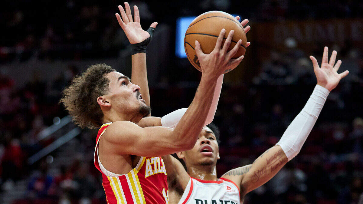 Atlanta Hawks guard Trae Young, left, shoots over Portland Trail Blazers guard Anfernee Simons during the first half of an NBA basketball game in Portland, Ore., Monday, Jan. 3, 2022. (AP Photo/Craig Mitchelldyer)