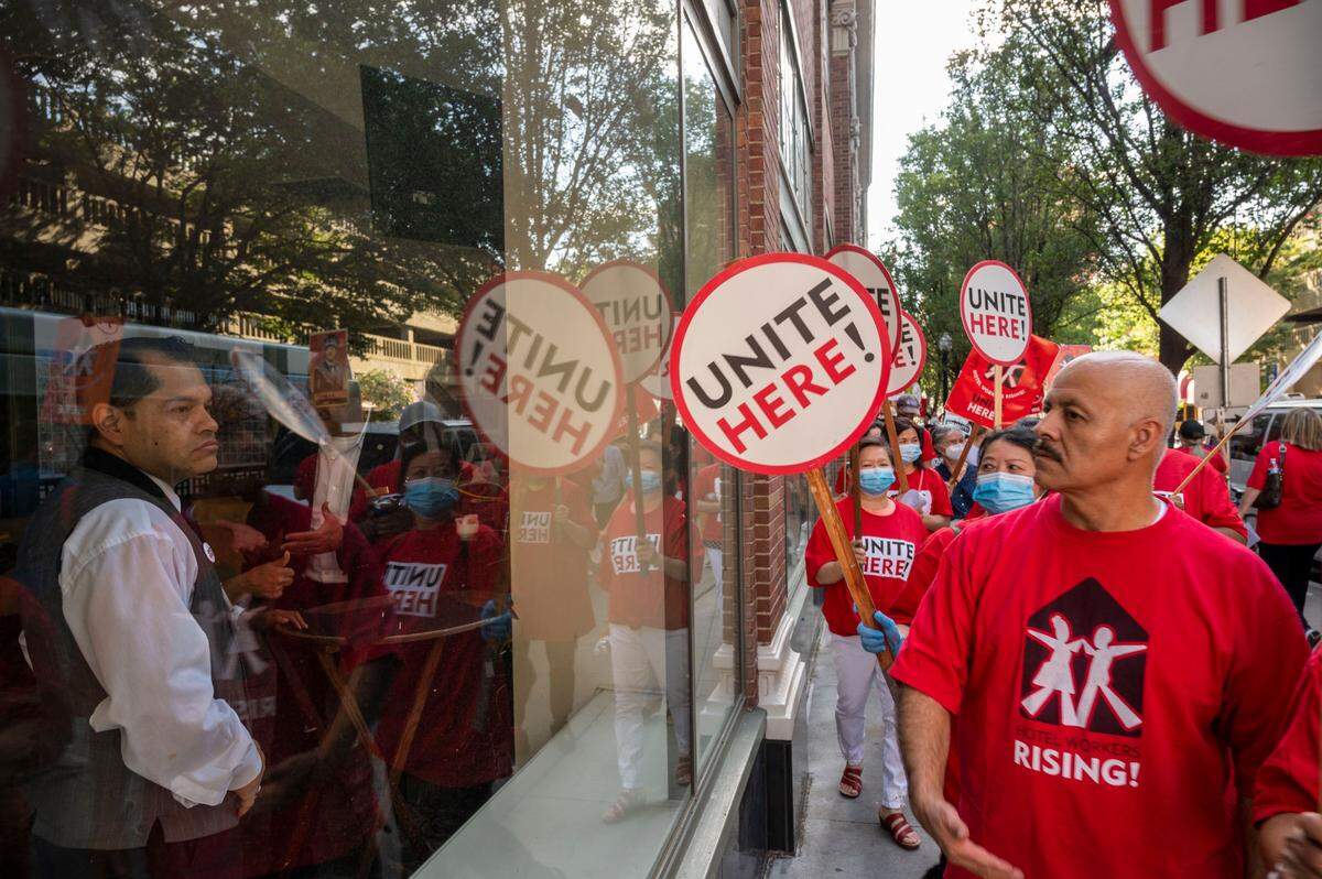 Sheraton Grand Hotel workers look out the window as Local 49 unite protesters rally in front of the Sheraton Grand Hotel in Sacramento on Wednesday to demand wage increases and address chronic short staffing.