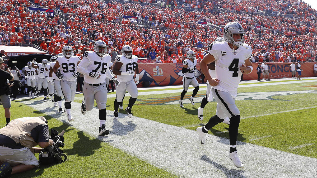 Quarterback Derek Carr (4) leads his Raiders teammates onto the field Sept. 16 in Denver. Oakland will be on the road for the second week in a row when the team visits the Miami Dolphins on Sunday.