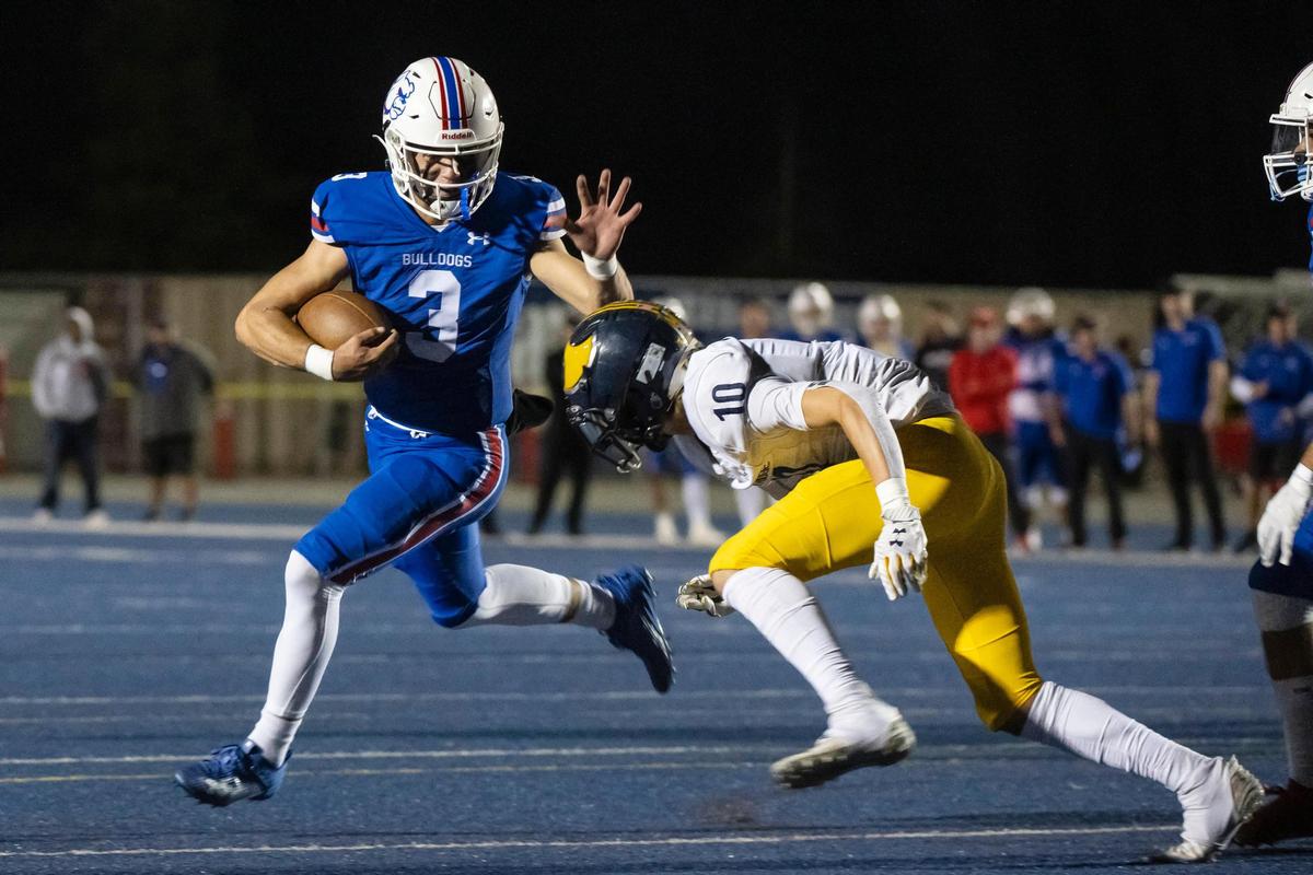 Folsom Bulldogs quarterback Ryder Lyons (3) breaks a tackle from Oak Ridge Trojans’ Jasen Womack (10) on Sept. 29.