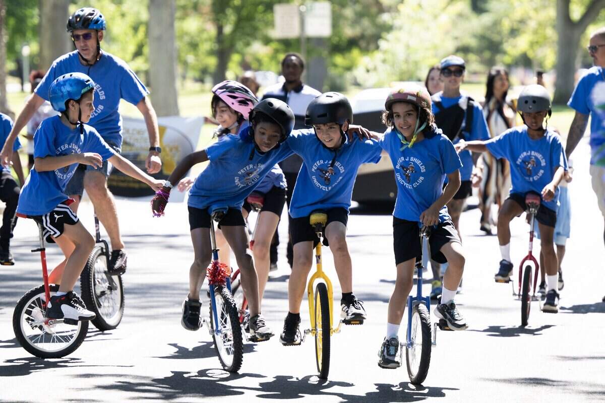 James Harris, Samir Mukhtar and Issac Rocha of the Peter Shields Unicycle Club embrace one another as they ride during the parade at the opening of the Juneteenth event in Land Park on Saturday, June 20, 2026, in Sacramento.