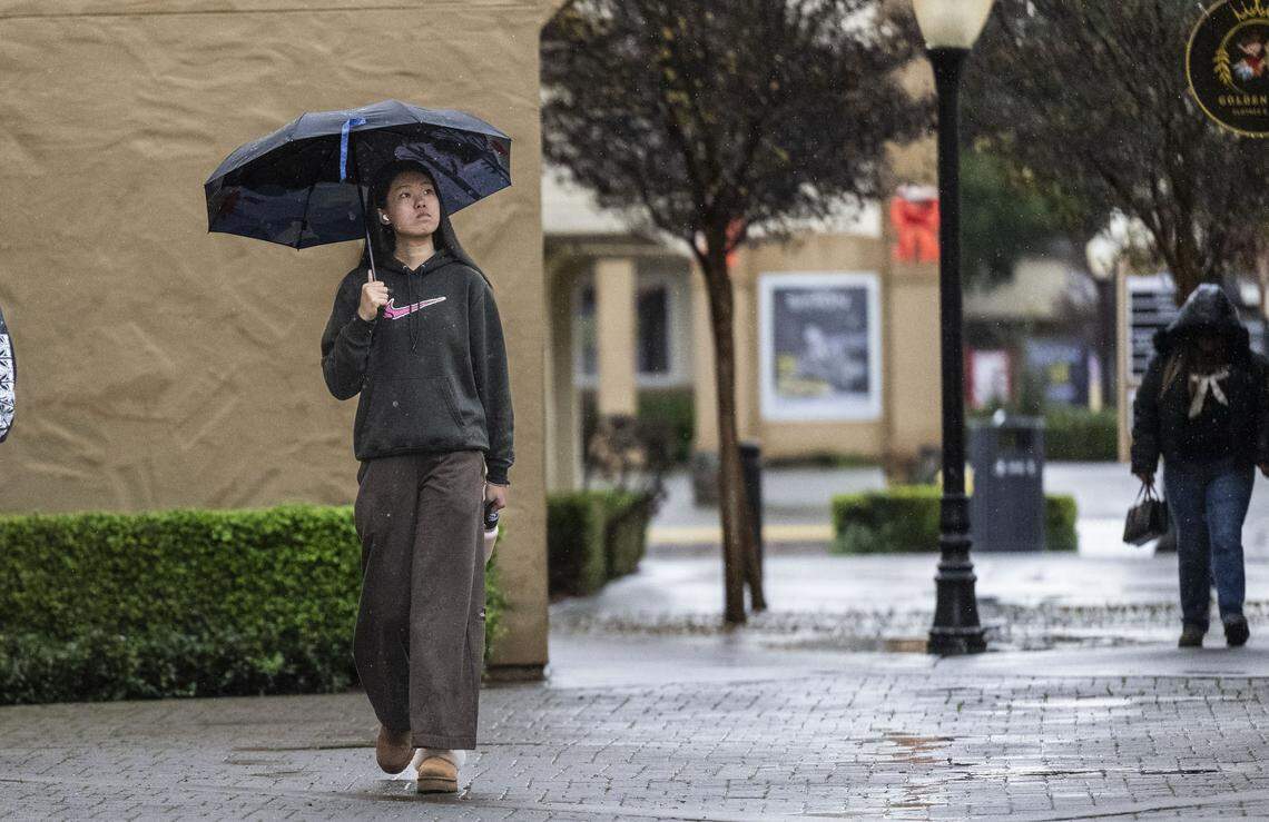 A customer walk in the rain at the Folsom Premium Outlets on Monday, Dec. 22, 2025.