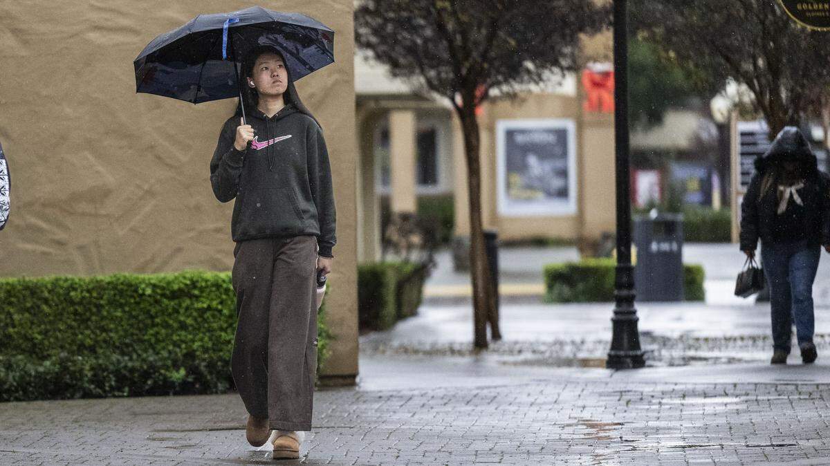 A customer walks in the rain at the Folsom Premium Outlets on Monday, Dec. 22, 2025. Stormy weather is expected in Northern California this coming week, forecast to bring rain to Sacramento after a mostly dry, foggy January.
