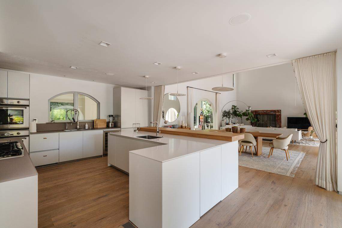 Sunlight streams into the soaring two-story living room and open European kitchen, where an arched gallery walkway seamlessly connects stylish entertaining areas and peaceful garden views.