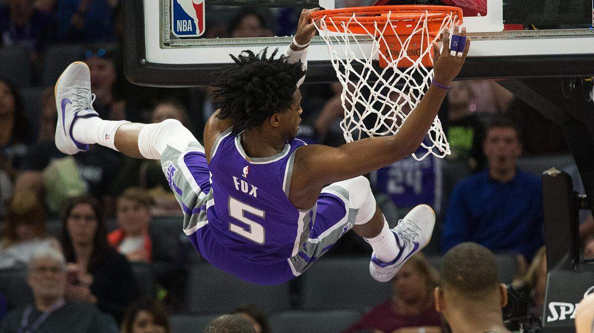 Kings guard De'Aaron Fox hangs on the rim after dunking against the Boston Celtics on March 25 at Golden 1 Center. An unverified NBA site on Twitter says the Kings are considering trading Fox.