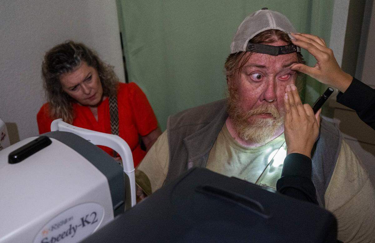 Maria Montano, a social worker at the Sacramento Public Library, sits next to Paul Jackson as he has his eyes checked on during an optometry appointment on June 10. Jackson lost vision on one of his eyes after he was beaten while walking home in Los Angeles.