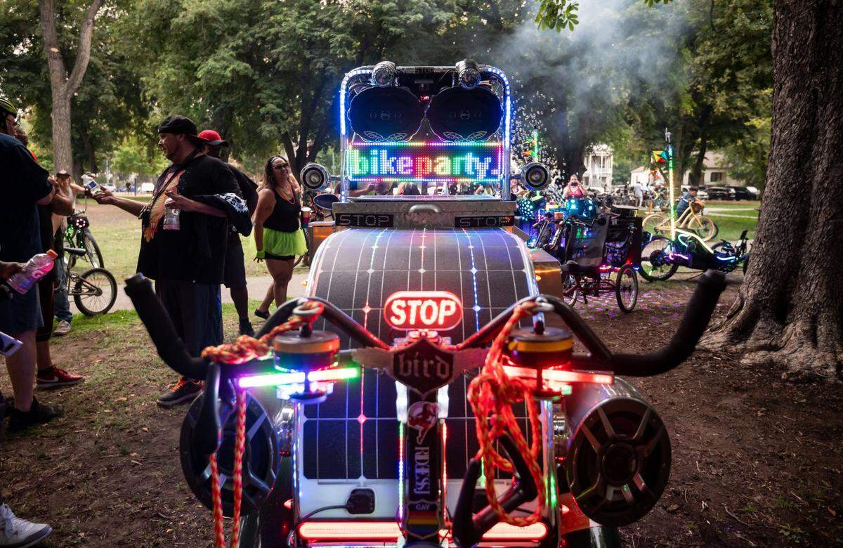 James Clement, left, of San Jose, socializes after arriving on his bike, featuring LED lights and a sound system, at Southside Park for the monthly Bike Party Sacramento ride Friday, Aug. 6, 2021, in Sacramento.
