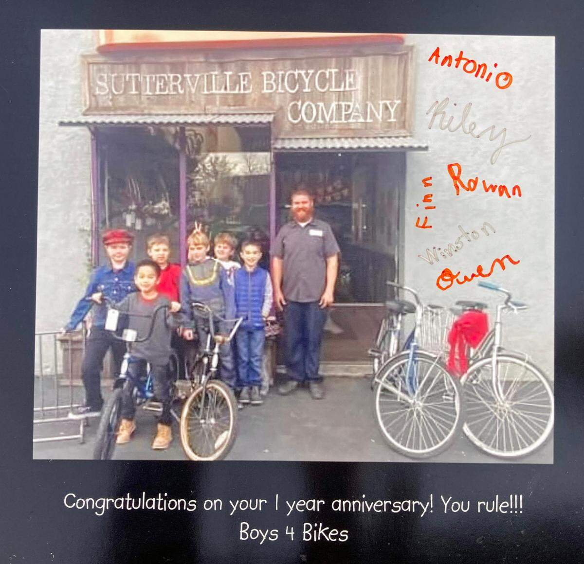 A 2014 photo displayed at Sutterville Bicycle Co. shows, with shop owner Jeff Dzurinko, the kids who founded the charity Boys 4 Bikes.