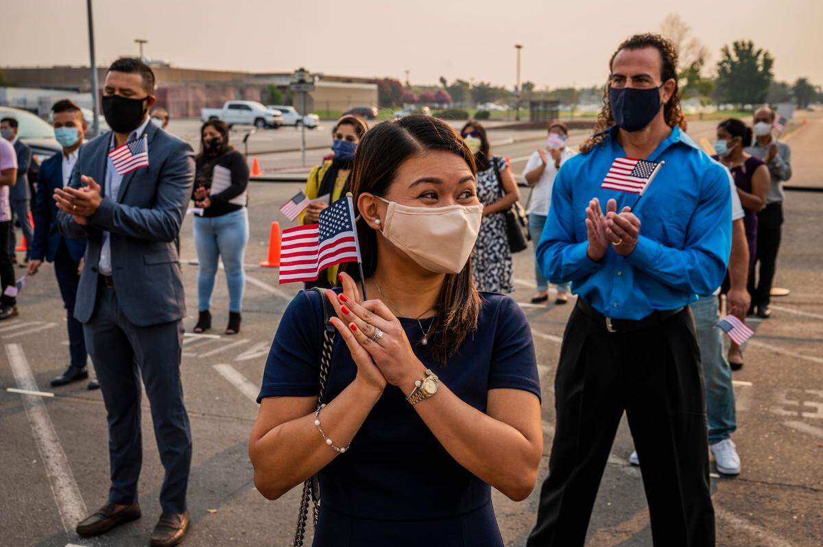 Elainne Rule of Roseville delights as she looks at her husband after she takes the naturalization oath at McClellan Conference Center on a smoky Tuesday morning, Aug. 25, 2020. Close to 575 people became citizens in multiple ceremonies throughout the day, standing on a socially distanced grid outside.