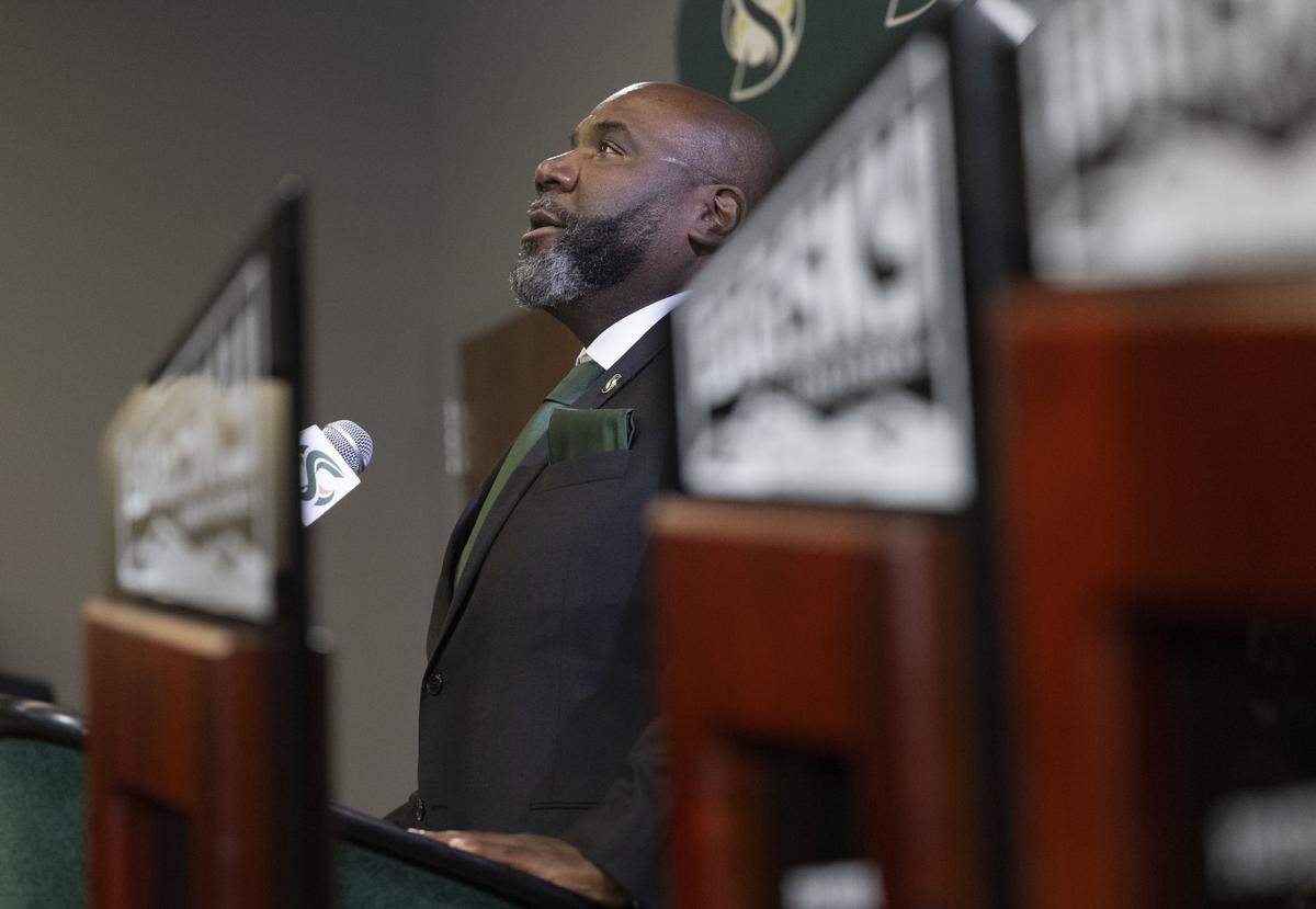 New Sacramento State football coach Alonzo Carter, framed by Big Sky championship trophes from previous seasons, acknowledges his late mother during an introductory press conference on Thursday, Dec. 18, 2025. Carter is the university's 14th head football coach.