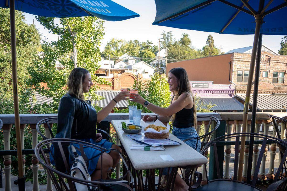 Mikayla Totushek, left, and Jillian Elenberger of Folsom enjoy a happy hour cocktail on the patio at Q’bole Cocina & Cantina in Folsom on Thursday. Restaurant owner Diane Calderon says business has really slowed since for lease signs were placed in front and on the back exterior wall of the establishment.