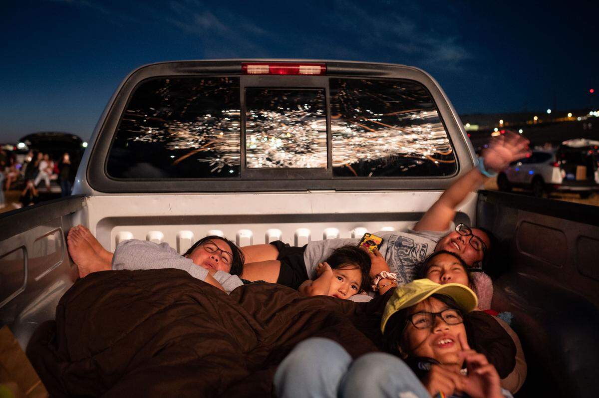 Elizabeth Divinagracia, left, of El Dorado Hills, and her daughters, clockwise from center, Callie, 6, Sky, 22, Hunter, 16, and Steele, 9, huddle together to watch the Star Spangled Drive In Independence Day fireworks finale on Friday, July 3, 2020, which was held south of Highway 50 in the planned Folsom Ranch community.