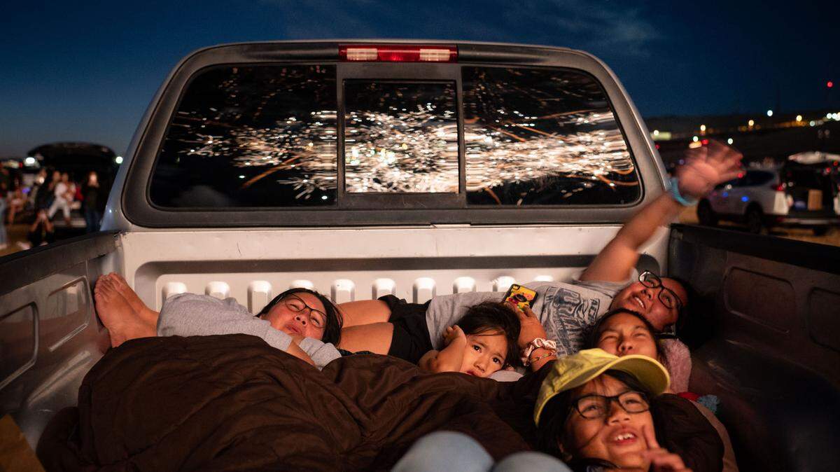 Elizabeth Divinagracia, left, of El Dorado Hills, and her daughters, Callie, 6, Sky, 22, Hunter, 16, and Steele, 9, huddle together to watch the Star Spangled Drive-In Independence Day fireworks finale on Friday, July 3, 2020, which was held south of Highway 50 in the planned Folsom Ranch community.