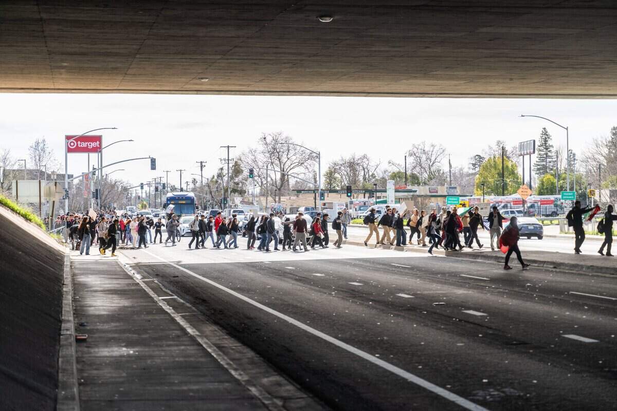 Students from Hiram Johnson High School cross 65th Street under the Highway 50 overpass in Sacramento during a walkout to protest President Donald Trump on Tuesday. The students marched to Sacramento State.