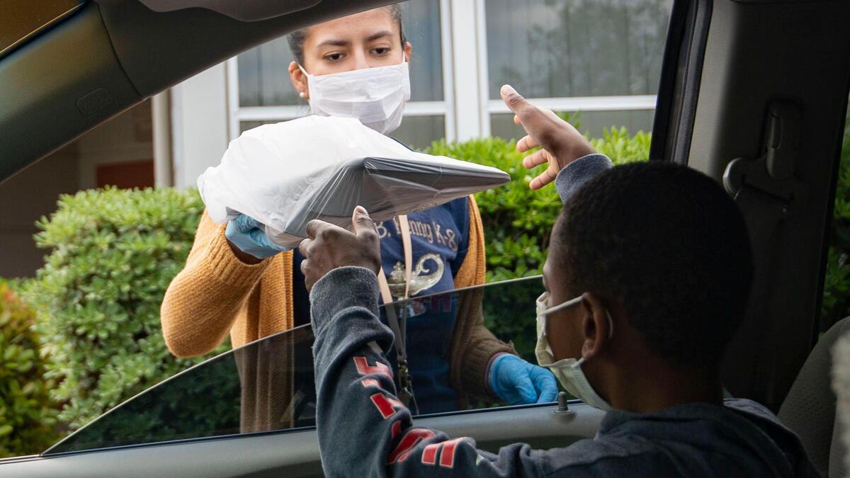 Third grader Knowledge Johnson, 9, takes a laptop from Sacramento City Unified School teacher Sara Nava to use while distance learning during the coronavirus pandemic, Friday, April 10, 2020, at Father Keith B. Kenny Elementary School in Oak Park. California schools are closed during the COVID-19 outbreak requiring students to continue the 2019-2020 school year from home. School districts around the state are helping supply laptops to students who may not have access to one at home.
