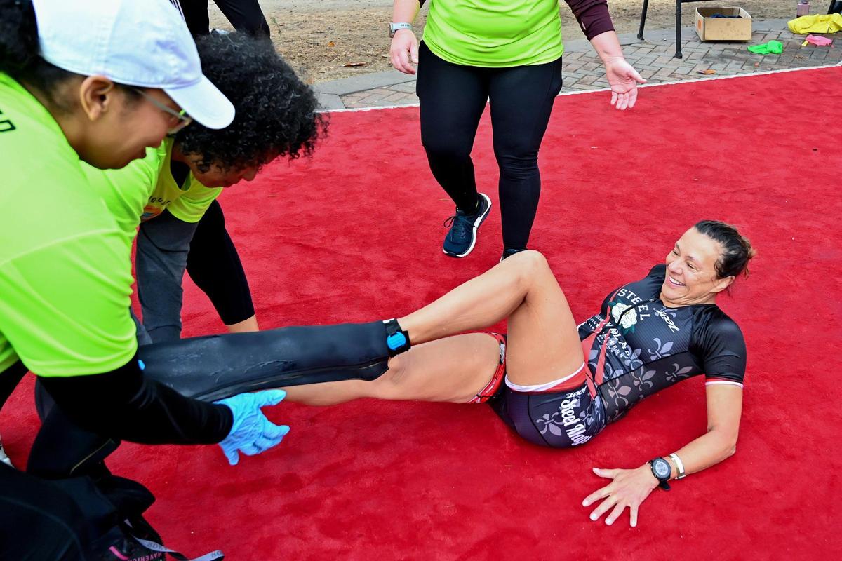 Angele Sanders, of New Orleans has her wetsuit removed by volunteers after finishing the swim portion during the Ironman California triathlon on Sunday.