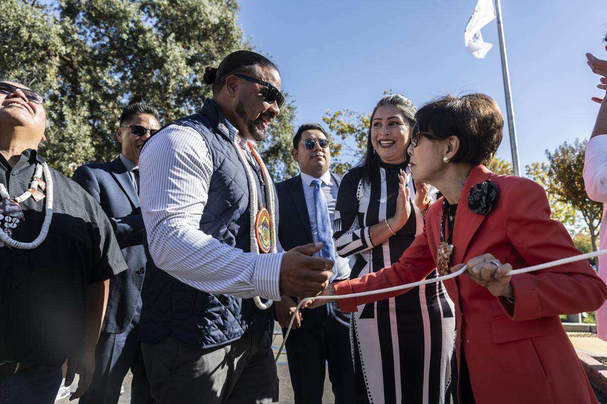 Wilton Rancheria chairman Jesus Tarango receives the flag cord from Rep. Doris Matsui, D-Sacramento, as his tribe's flag is raised at Elk Grove City Hall on Monday.