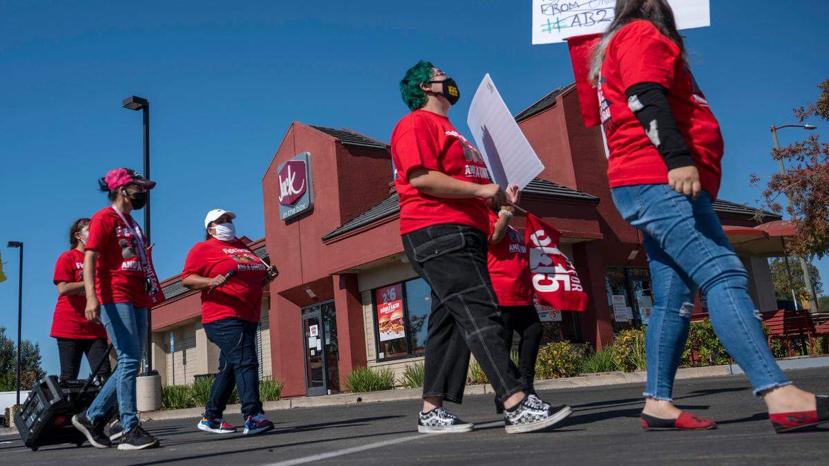 Workers and supporters march Friday, Oct. 15, 2021, at a Jack in The Box restaurant on Greenback Road in Folsom, where they say management threatened to call immigration enforcement after the employees made complaints about wage theft, a lack of meal or rest breaks, and safety issues related to COVID-19. The Labor Commissioner’s Office remains understaffed as a backlog of wage theft complaints continue piling up.