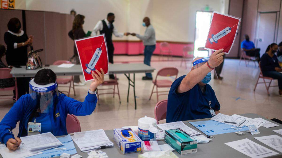 Nurses hold up signs during a free COVID-19 vaccination drive in Oak Park in April 2021. Vice Mayor Schenirer and Sutter Health will hold a vaccination drive at Colonial Park on August 3, 2021, as the delta variant continues to drive up case numbers in Sacramento County.