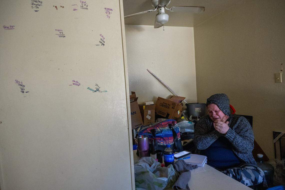 Kristi Phillips, 49, cries Monday between making phone calls looking for housing help for her and her son. An eviction notice had been posted Friday at the Sacramento apartment where they were living. She said her daughters, ages 9 and 10, were staying with their father because of her housing situation. Markings on the wall at left indicate their heights, and those of family members. “I can’t lose my kids because of this,” she said.