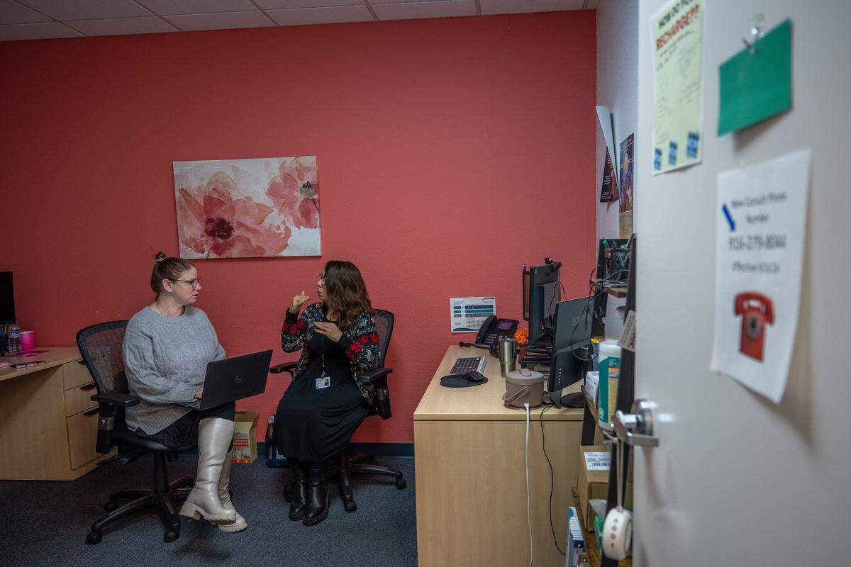 Outreach and volunteer worker Maria Ancona, right, discusses how she handles 988 crisis phone calls with Vered DeVries, a crisis administrative assistant, at WellSpace Health in Sacramento in December. 