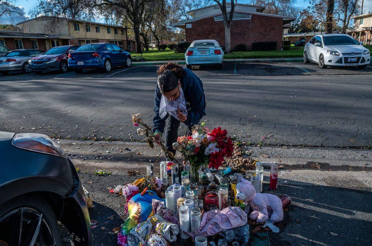 Jasmine Singh straightens up a memorial where Isabel Agnes Delgadillo Martin, 7, was shot and killed alongside Clifford Hall while walking in the housing development last month on Dec 14. She says she doesn’t want the community to be known for the shooting because it was people outside who came in and shot them.