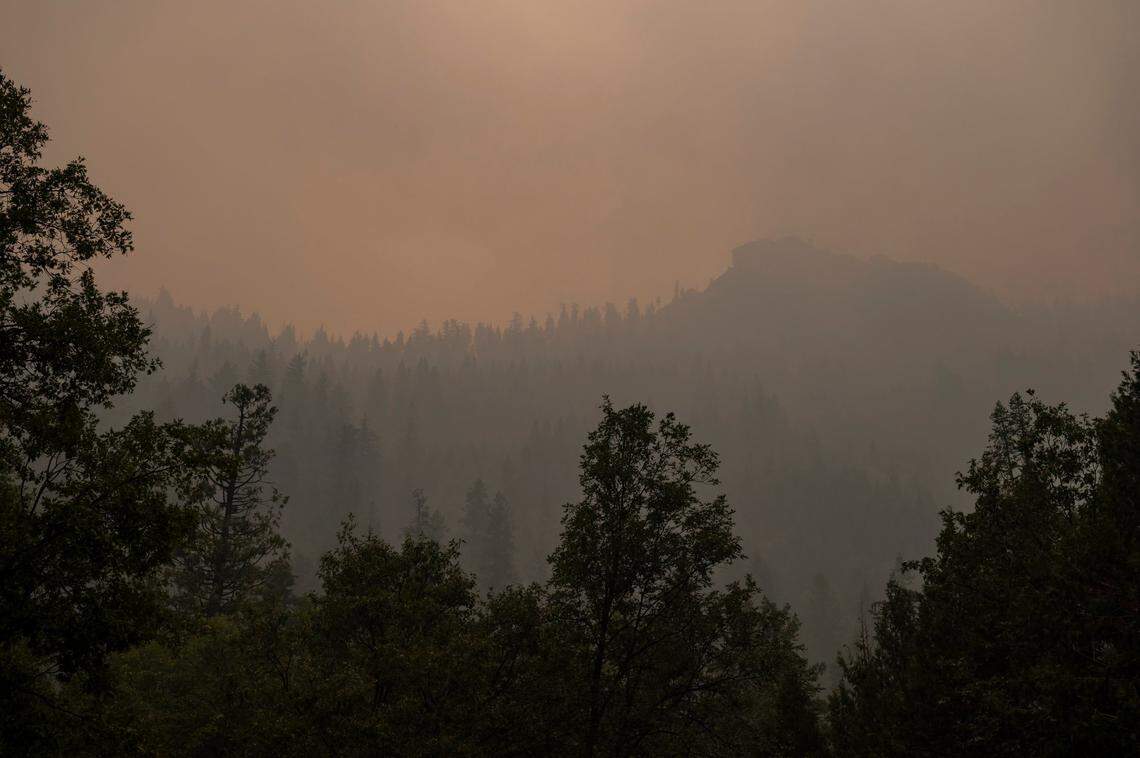 Smoke fills the sky as the the Caldor Fire burns behind Eagle Rock on Highway 50 near Kyburz on Sunday. Firefighters are stationed at turnouts on the highway from Kyburz to South Lake Tahoe to watch for spot fires, one firefighter said, after the wildfire jumped 50.