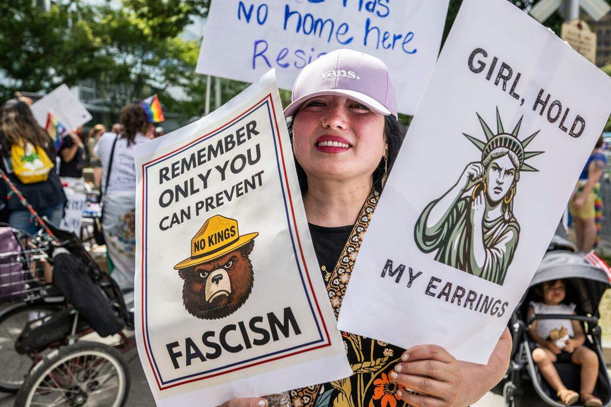 Sylvia Romo, of Sacramento, holds signs during the “No Kings” rally at the state Capitol on June 14.