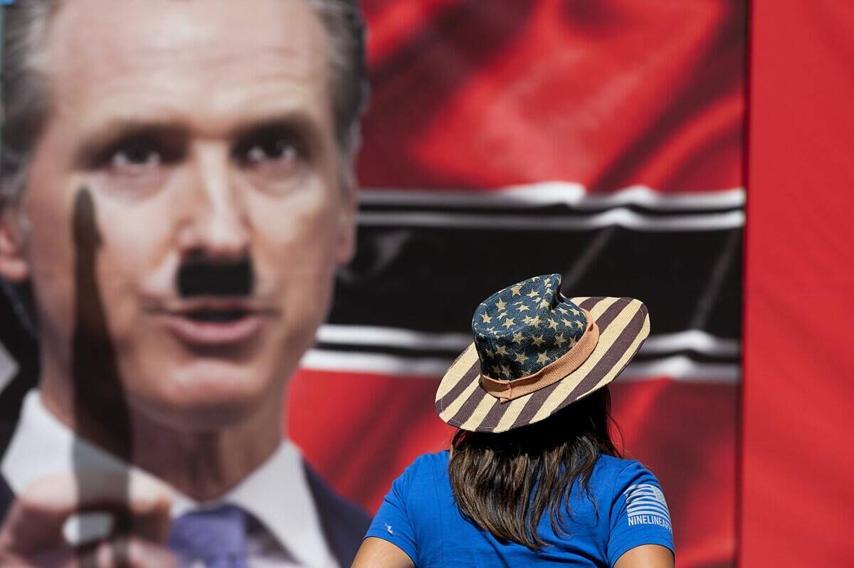 A banner of California Gov. Gavin Newsom with an Adolph Hitler mustache is unfurled during a protest at the state Capitol on Thursday, May 7, 2020 in Sacramento during the coronavirus pandemic.