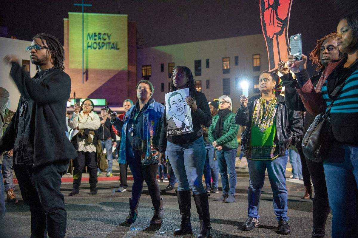 Protesters hold signs protesting the Sacramento County DA’s decision in the Stephon Clark case Monday in front of Mercy Hospital in East Sacramento. The march ended with more than 80 people arrested.