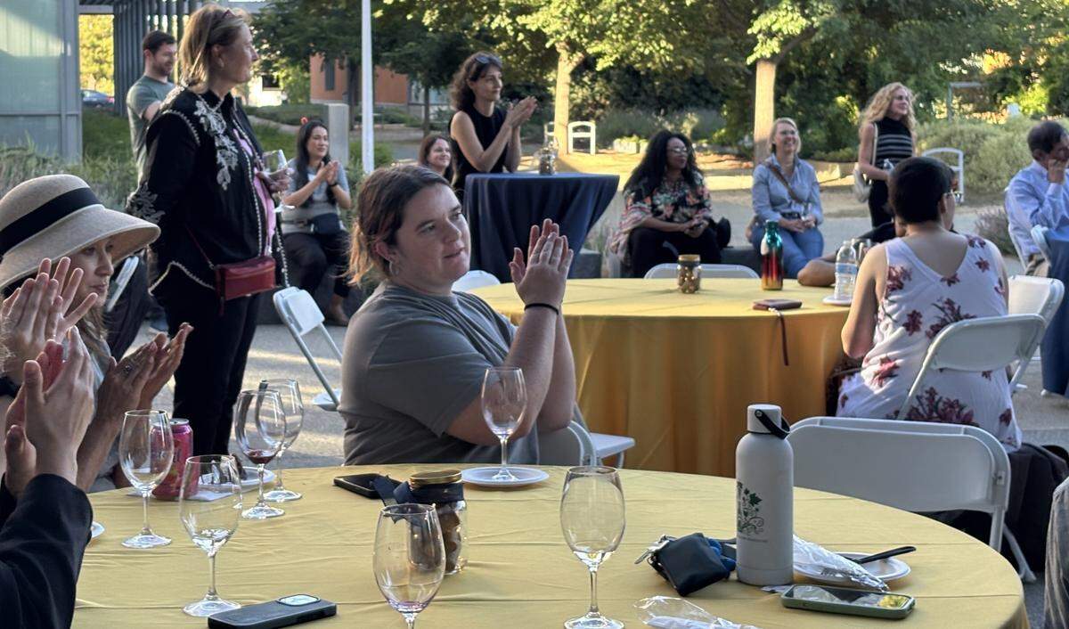 Megan Hill, a first year graduate student in the viticulture and enology department, claps for professor David Block’s speech at a student wine sale debut party on Wednesday, June 11, 2025.