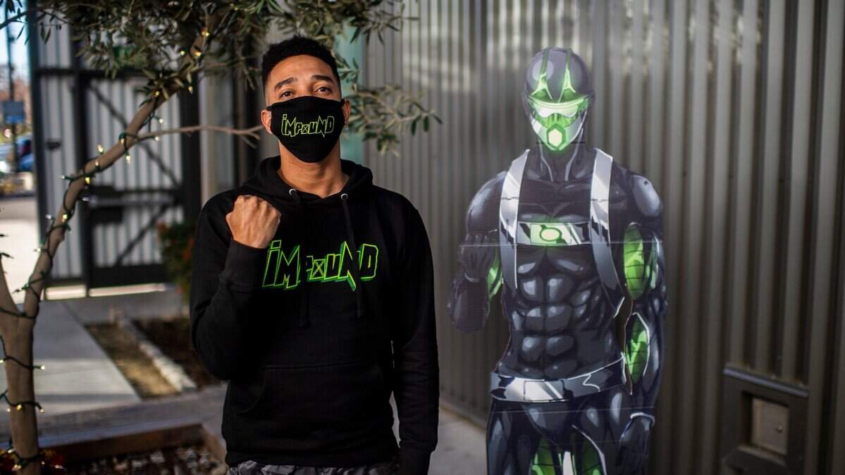 Impound Comics creator Brent Trayce Sands mimics the pose of a cutout of his character Anthony “Impound” Endsley on Tuesday, Dec. 29, 2020, in midtown Sacramento. His comic book superhero is a Black single father and MMA fighter and Sacramento landmarks are prominently featured in his work.