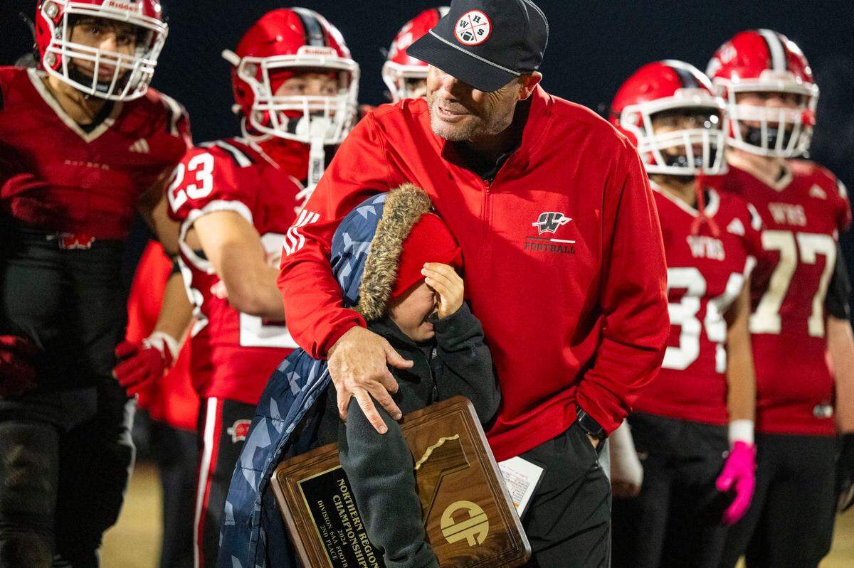 Winters coach Daniel Ward consoles his son Declan, who is holding the Division 6-AA second place plaque, after the Warriors lost the 2024 CIF Northern California regional football championship game to the Arcata Tigers in Winters.