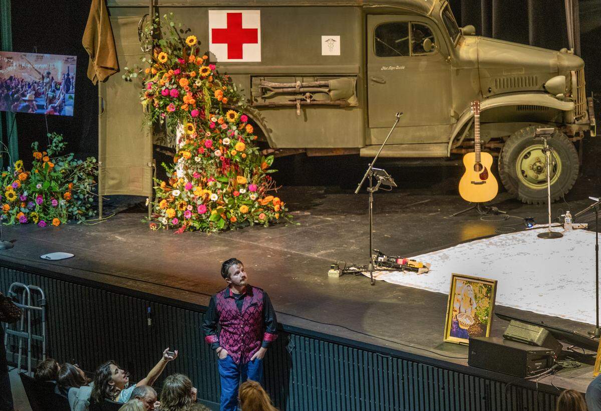 Gabriel Smith looks up at pictures of his mother, flight nurse Suzie Smith, on a big screen at her memorial service at the Redding Civic Auditorium on Friday, Nov. 14, 2025. She sustained critical injuries in a medical helicopter crash in October and died a few days later in Sacramento. As people were arriving for the service, Smith said the outpouring of community support was heartwarming.