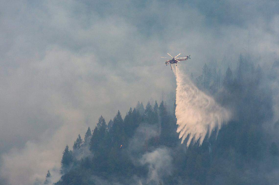A Sikorsky S-64 Skycrane drops water on the ridge near Baltimore Mine Road during the Mosquito Fire on Sunday.