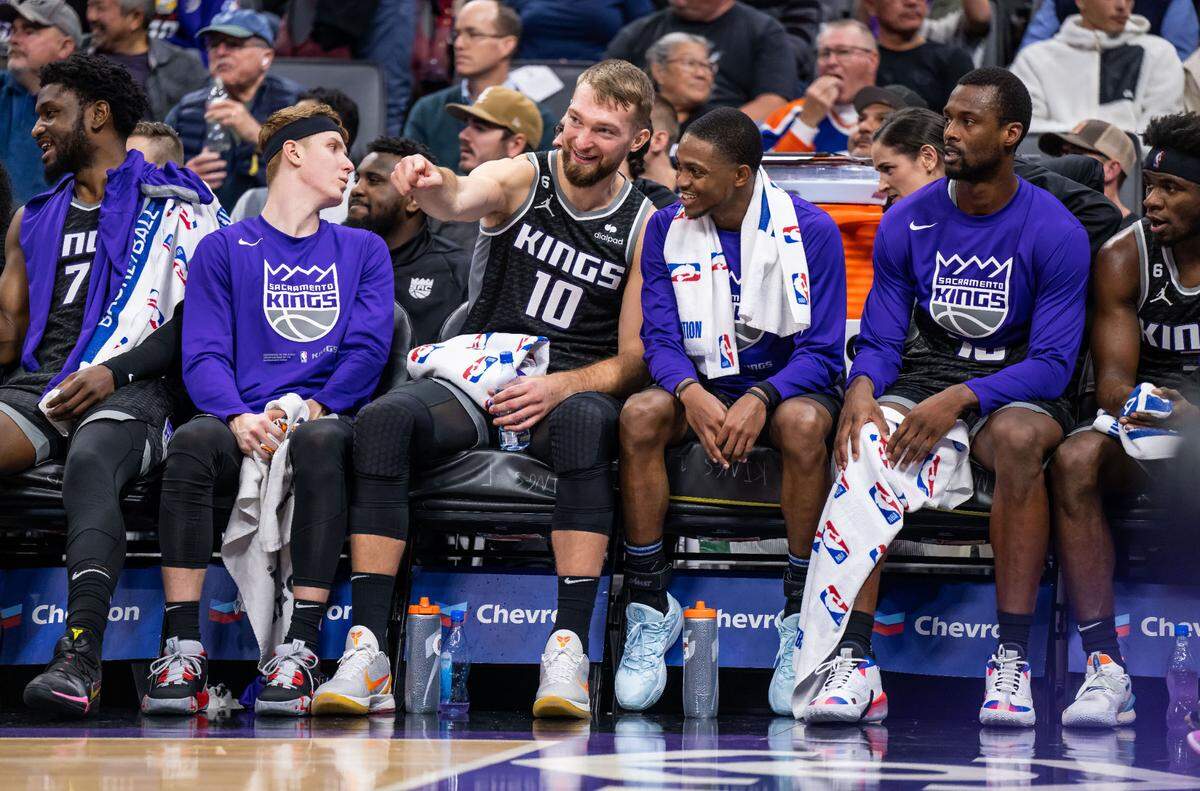 Sacramento Kings center Domantas Sabonis (10) and guard De’Aaron Fox (5), center, smile from the sideline as the Kings hold a insurmountable lead over the Indiana Pacers during the fourth quarter of the NBA basketball game Wednesday, Nov. 30, 2022, at Golden 1 Center in Sacramento. Flanking them are teammates, from left, center Chimezie Metu (7), guard/forward Kevin Huerter (9), forward Harrison Barnes (40) and guard Terence Davis II (3).