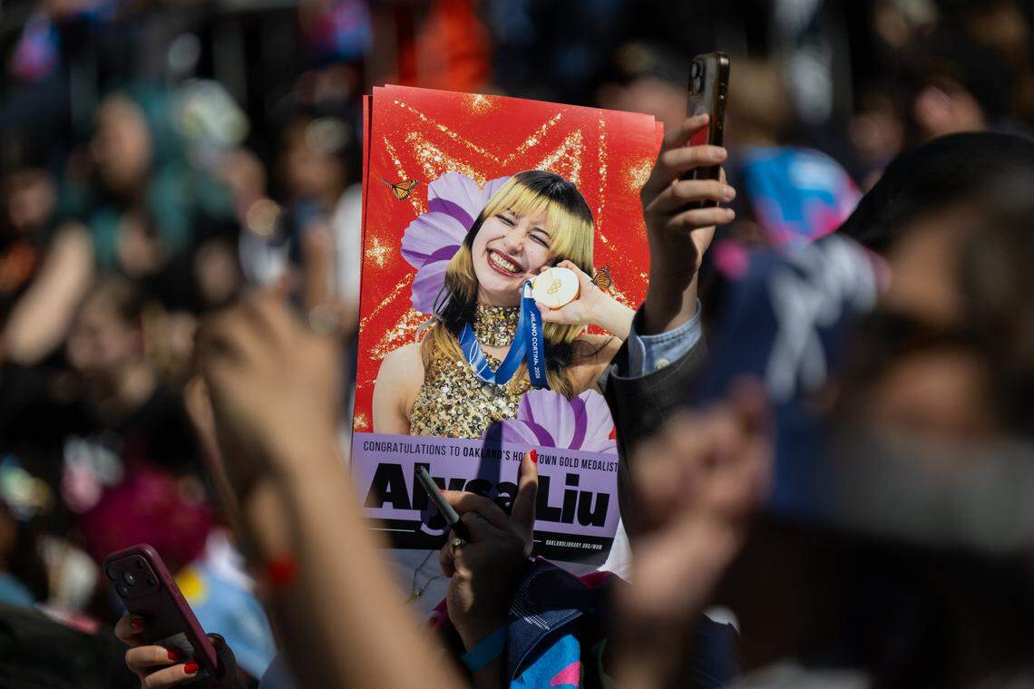 A member of a crowd of thousands holds a picture of Olympic gold medalist Alysa Liu during a celebration in her honor at Frank Ogawa Plaza in Oakland on Thursday.