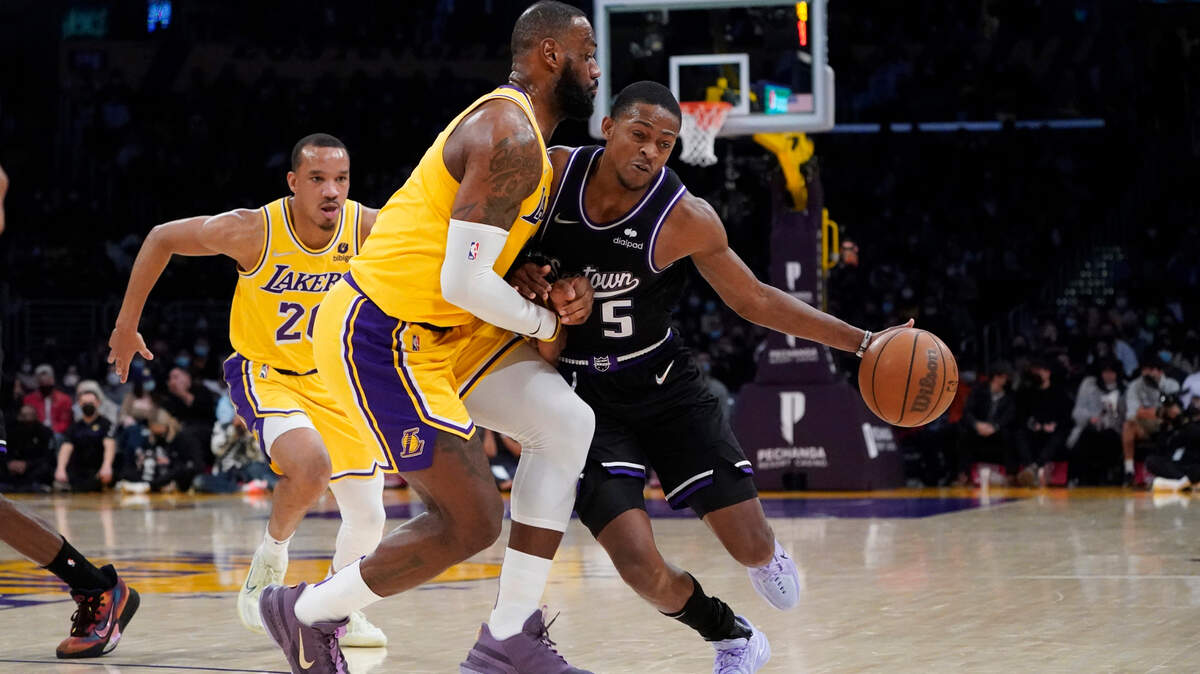 Sacramento Kings guard De’Aaron Fox (5) is defended by Los Angeles Lakers forward LeBron James during the second half of an NBA basketball game Tuesday, Jan. 4, 2022, in Los Angeles. (AP Photo/Marcio Jose Sanchez)
