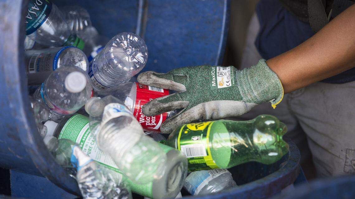 A worker at rePlanet recycling center in North Sacramento dumps plastic bottles into a bin in 2016.