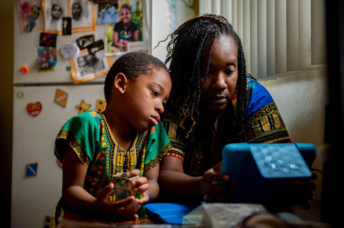 Tulley Smith, 6, a first-grader at Leataata Floyd Elementary School, works with his mom Marcheri Smith on online distance learning in their home in Sacramento on Friday, Oct. 2, 2020. Smith and her son have been struggling with distance learning because of unreliable internet and the lack of social activities for Tulley.