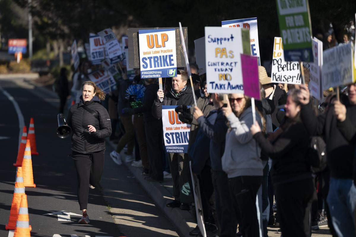 Striking medical workers wave signs outside Kaiser Permanente’s Roseville Medical Center in Roseville on Monday.