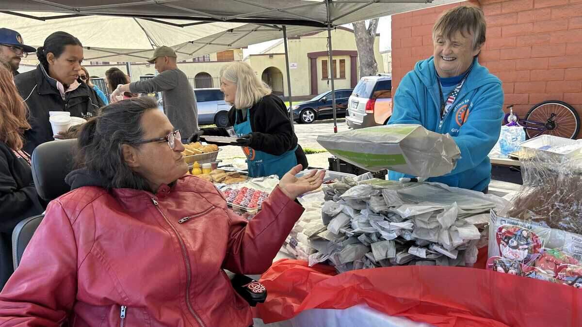 Kathy Luce, a volunteer for Lifting Spirits Higher, hands a meal to Leota Canady on Saturday at 2110 Del Paso Blvd. in Sacramento. 