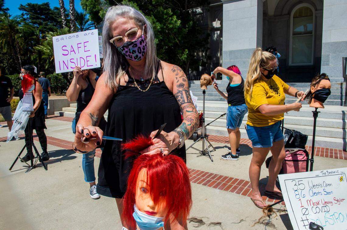 Kimberly Morris of Walnut Creek cuts the hair of a mannequin with other hairdressers at the Capitol in downtown Sacramento on Aug. 11, 2020, as part of a protest against state coronavirus restrictions prohibiting salons from operating indoors.