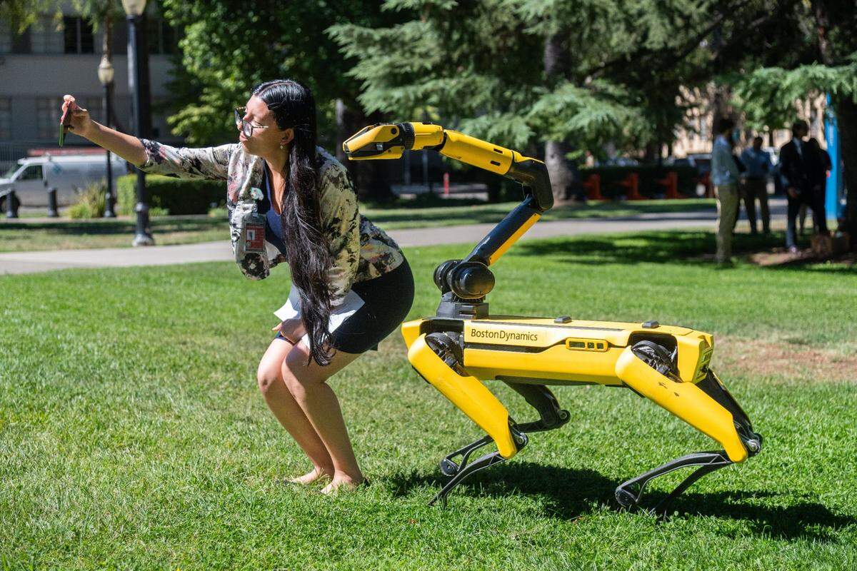Malluli Cuellar takes a selfie with Boston Dynamics’ robot dog Spot outside the state Capitol on Aug. 15, 2024. Caltrans has used similar Spot robots for security and inspections, including a six-month pilot in San Bernardino where the robot recorded footage of individuals on maintenance yard property after hours.